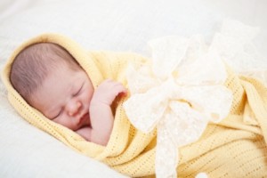 sleeping newborn baby wrapped in a yellow blanket